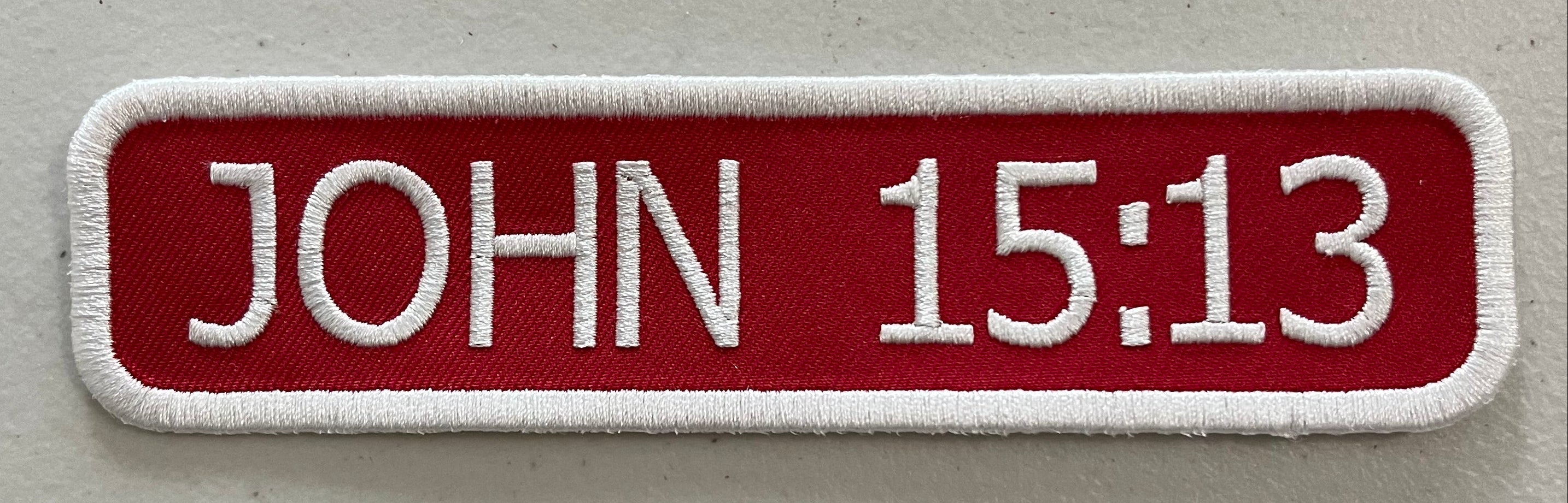 A custom embroidered patch on red background with white stitching.